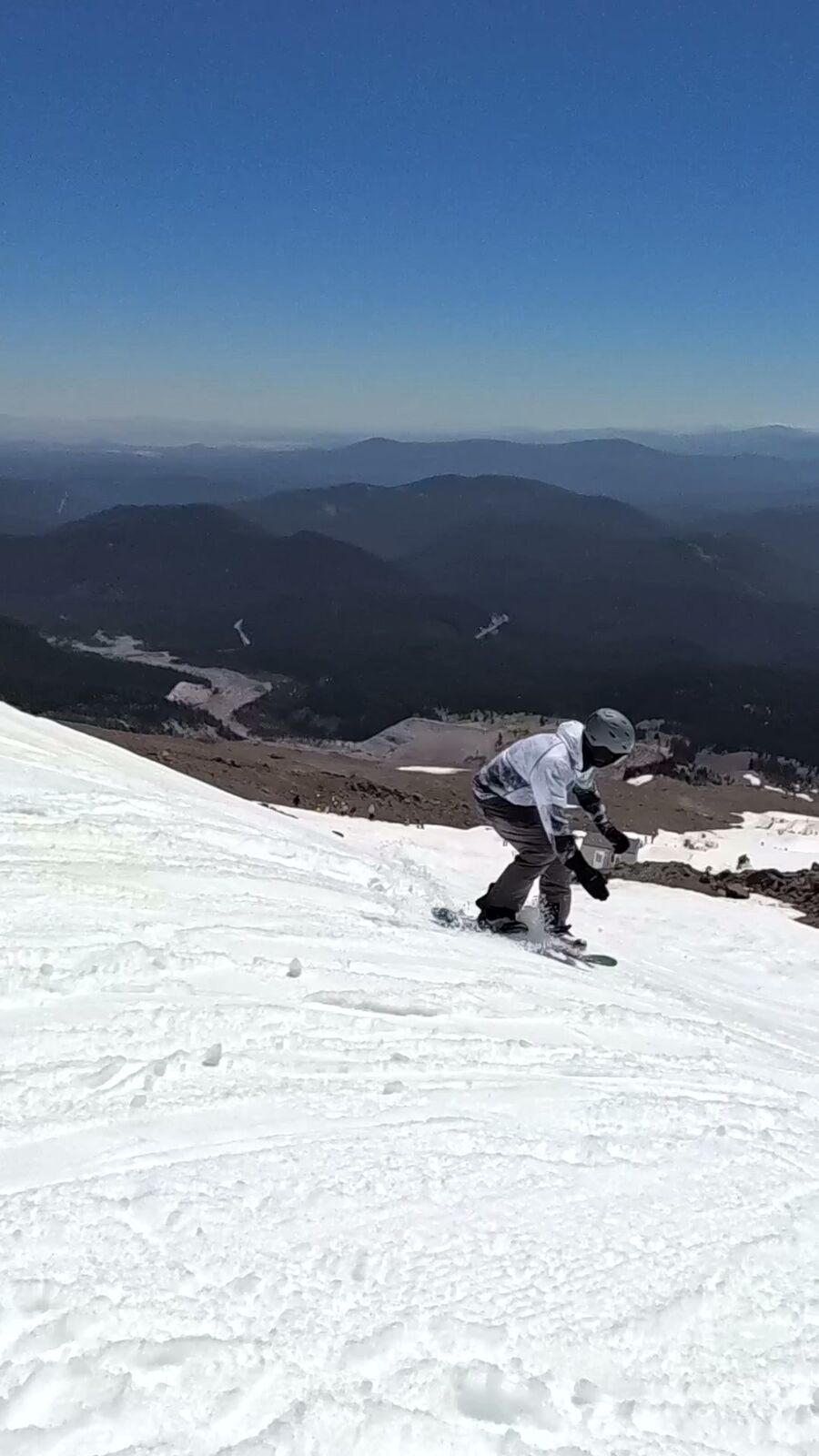 Rider on the summer glacier at Mt. Hood with mountains beyond