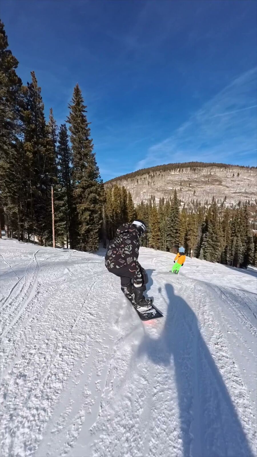 Snowboarder riding away down the slope